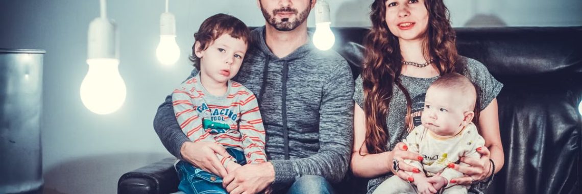 A loving family portrait with parents and children sitting together in a modern, well-lit room.