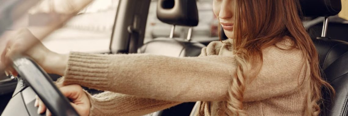 Side view of concentrated contemporary female driver in casual clothes going along street road alone by car with leather interior